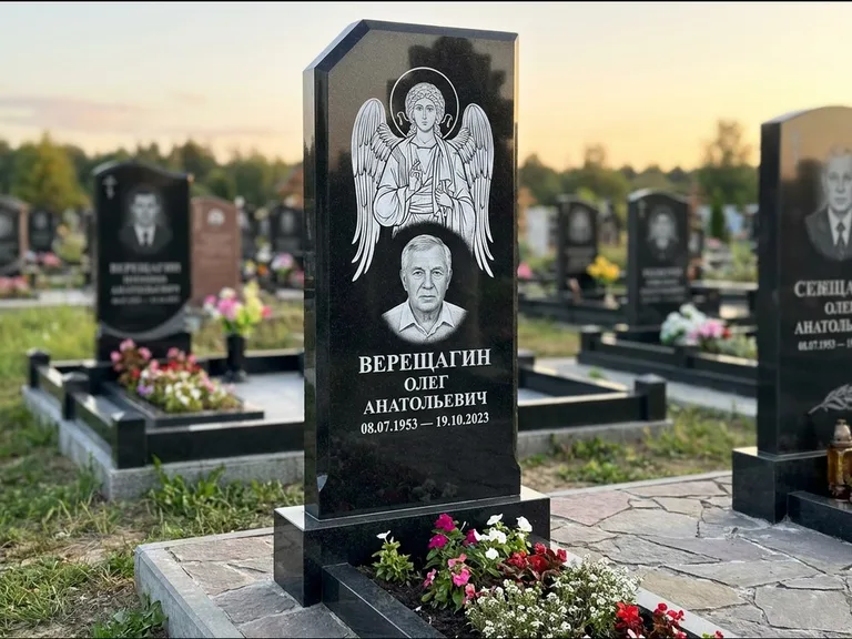Памятник с гравировкой иконы: стела с резным навершием и нимбом в золоте — гравировка образа Спасителя, высокие разросшиеся туи полукругом, работа «Мельникова» в Тольятти