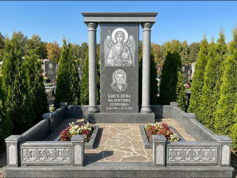 Памятник с гравировкой иконы: массивная стела с двускатным навершием-домиком — гравировка Николая Чудотворца, живая изгородь из туи, работа «Журавлёв» в Тольятти