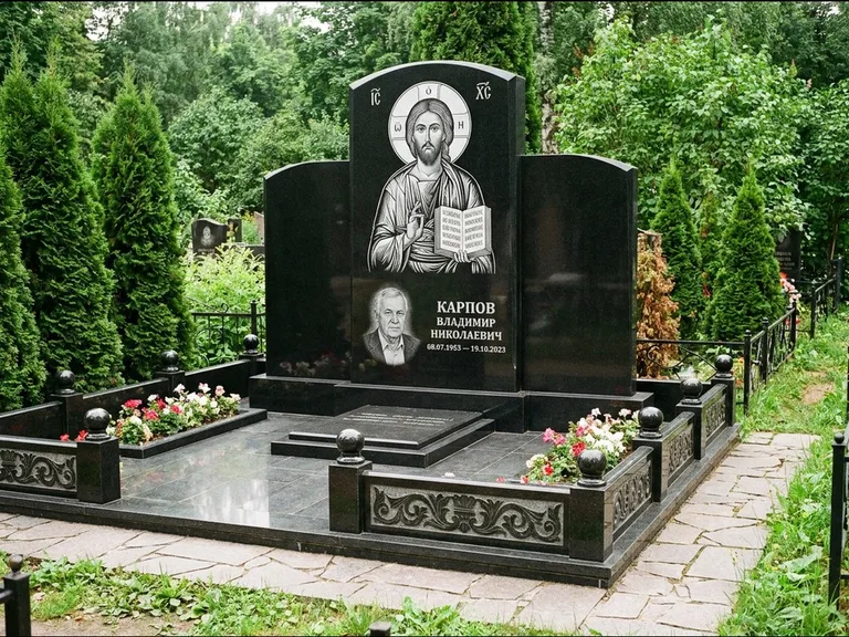 Памятник с гравировкой иконы: широкая панорамная стела с золочёным нимбом — гравировка образа Матроны Московской, цветник с белыми хризантемами, работа «Мельникова» в Тольятти