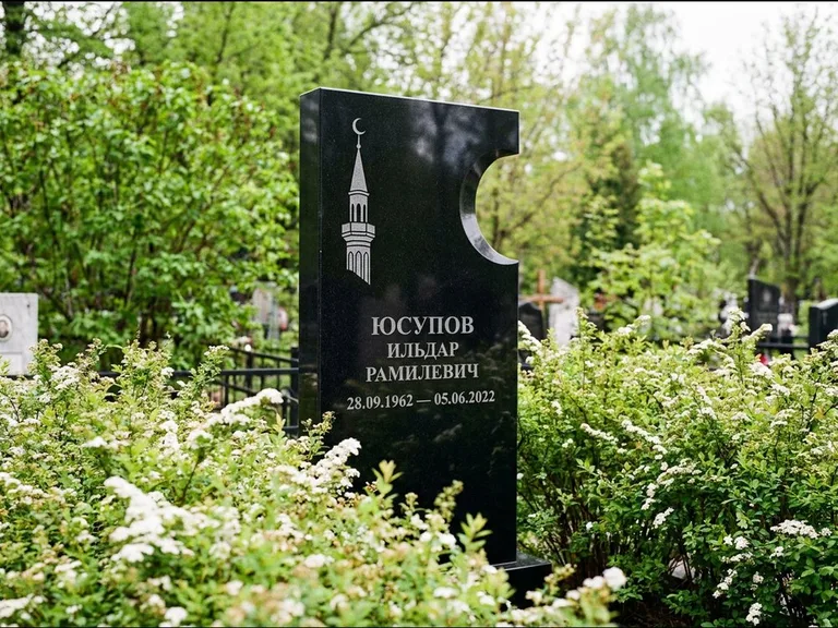 Мусульманский памятник с гравировкой мечети: стела с боковым вырезом в форме полумесяца — гравировка минарета с полумесяцем, низкие кусты спиреи в цвету, работа «Юсупов» в Тольятти