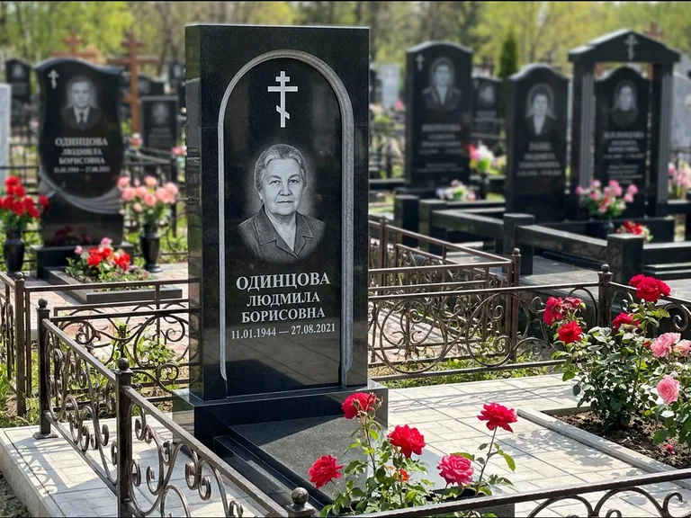 Памятник из чёрного гранита — скромная невысокая стела с крестом с терновым венцом, работа «Лаврентьева» в Тольятти