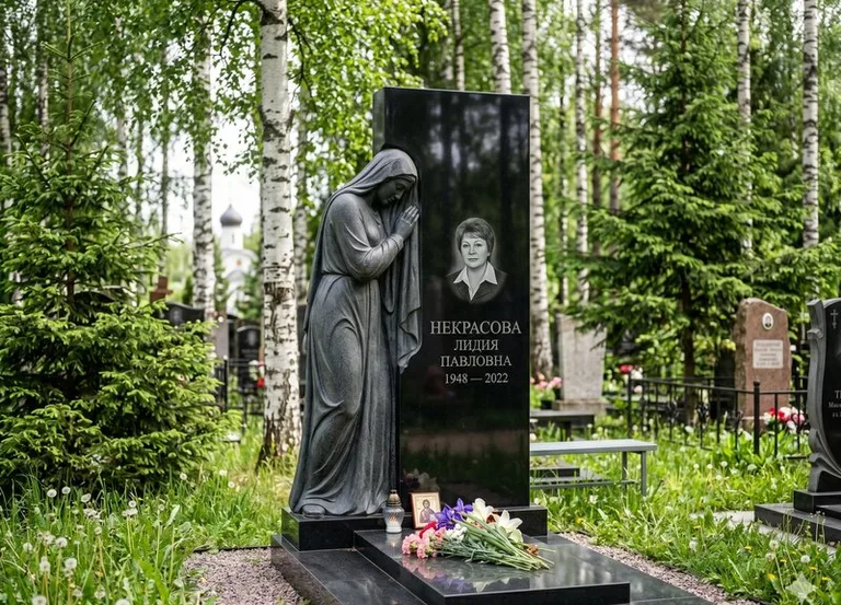 Гранитная фигура скорбящего мужчины у чёрной стелы в Тольятти